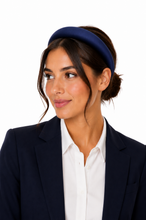 Load image into Gallery viewer, Girl in work wear wearing a navy satin padded headband against a white background with low bun.
