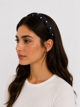 Load image into Gallery viewer, Woman wearing a black headband with white polka dots on a plain background
