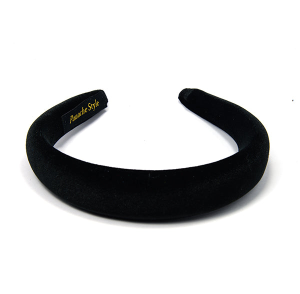 A black velvet padded headband on a white background with the brand name 'Panache Style' visible on a label on the inside of headband.